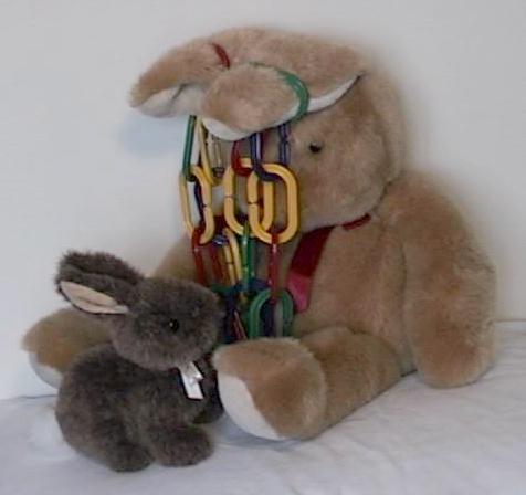 Big bunny holds colourful chain over little bunny, by its floppy ears!